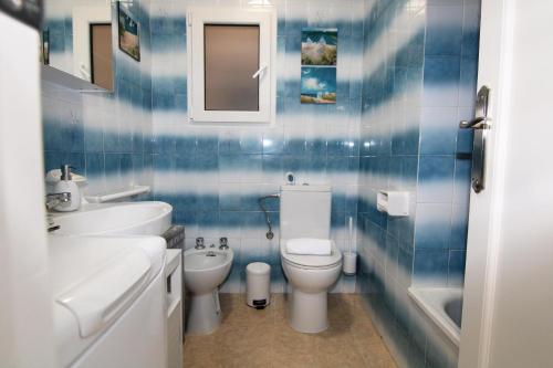 a blue tiled bathroom with a toilet and a sink at Santa Ana in Denia