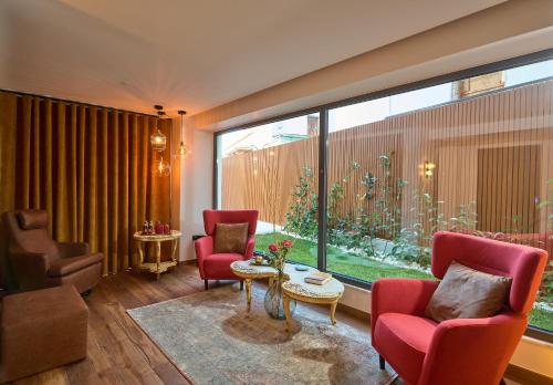 a living room with red chairs and a large window at SIGMA Suites Hotel in Thessaloniki