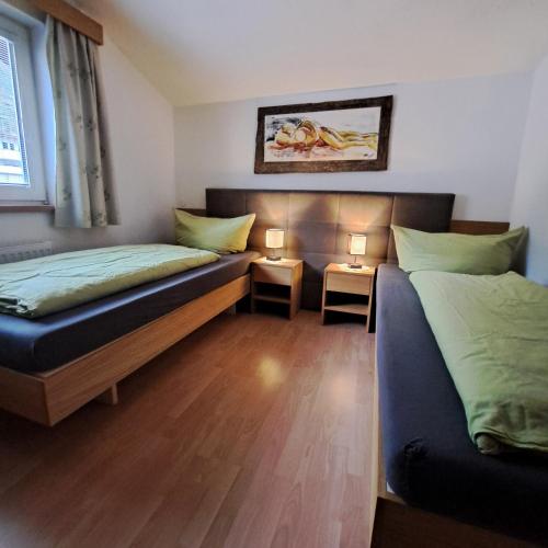 two beds in a room with two lamps on tables at Ferienwohnung Kobler in Landeck
