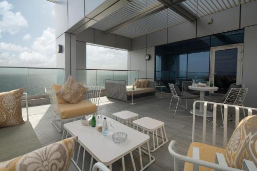 a balcony with tables and chairs and the ocean at Novotel Jazan in Jazan