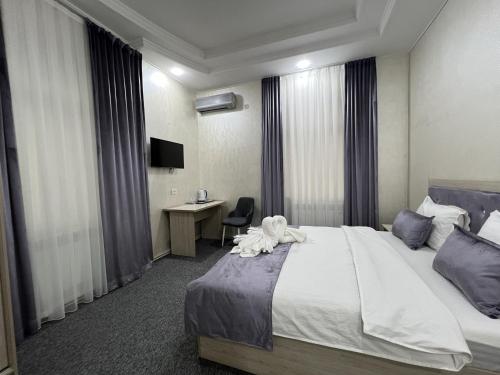 タシュケントにあるArt Tashkent Hotelのベッドとデスクが備わるホテルルームです。