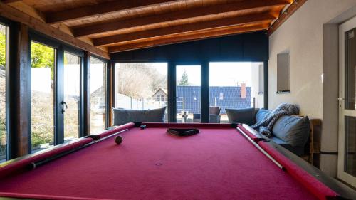 una mesa de billar rojo en una sala de estar con ventanas en Family Apartman, en Eplény