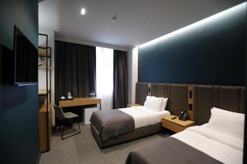 a hotel room with two beds and a desk at Graf Hotel in Tbilisi City