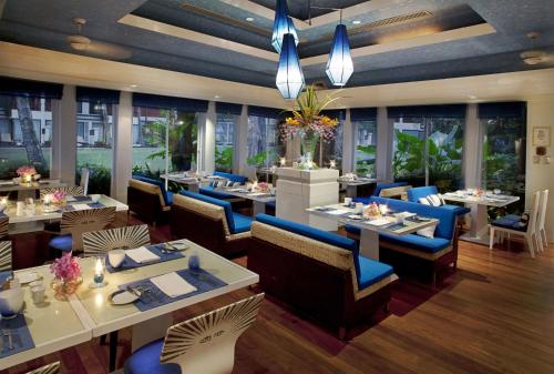 a restaurant with tables and blue chairs and windows at Dusit Thani Laguna Phuket in Bang Tao Beach