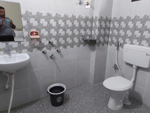 a man taking a picture of a bathroom with a toilet and sink at Hotel Lilac Doors in Patna