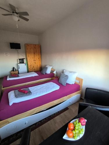 a room with two beds and a table with a bowl of fruit at Penzion U Ježů - Ubytování in Pasohlávky