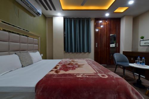 a hotel room with a bed and a desk and a table at Hotel Lilac Doors in Patna