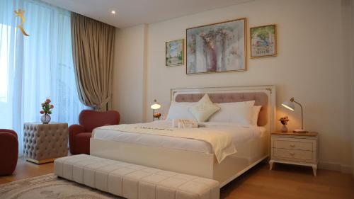 a bedroom with a large white bed and a chair at Luxuria 2BR Soul Beach Mamsha Al saadiyat in Abu Dhabi