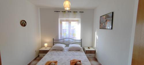 a bedroom with a bed with two pillows and a window at Apartman Mirna in Sumartin