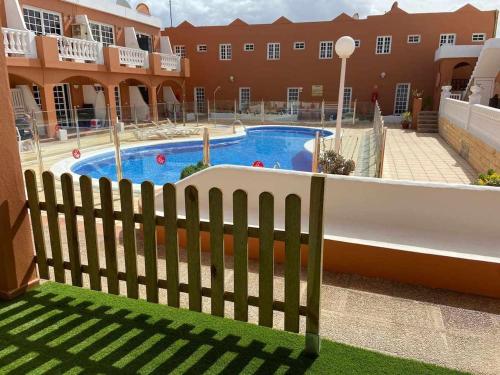 a wooden fence in front of a swimming pool at El Olivar Caleta Mar in Caleta De Fuste