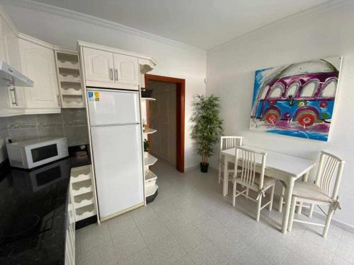 a kitchen with a table and a painting of a bus at El Olivar Caleta Mar in Caleta De Fuste