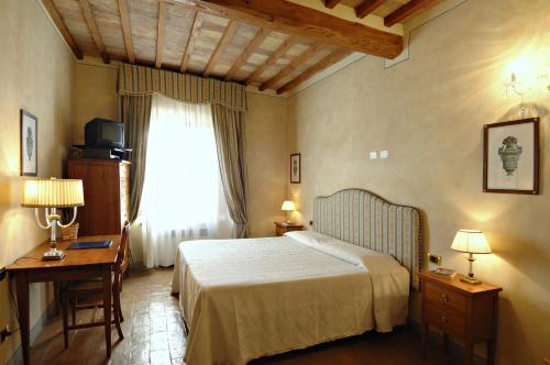 a bedroom with a bed and a desk and a window at B&B Palazzo Al Torrione in San Gimignano