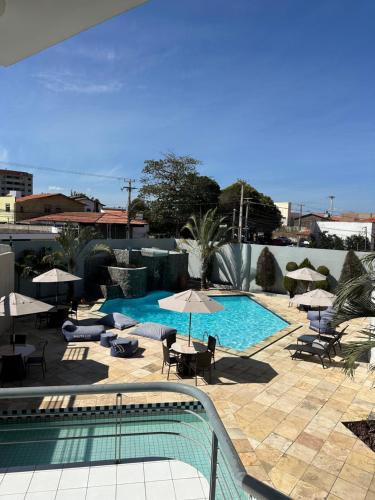 a swimming pool with umbrellas and tables and chairs at Nautillus Hotel in Parnaíba