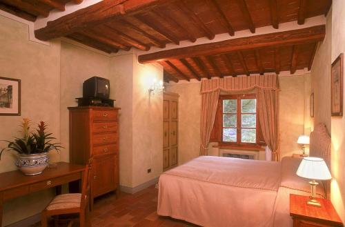 a bedroom with a bed and a dresser and a television at B&B Palazzo Al Torrione in San Gimignano