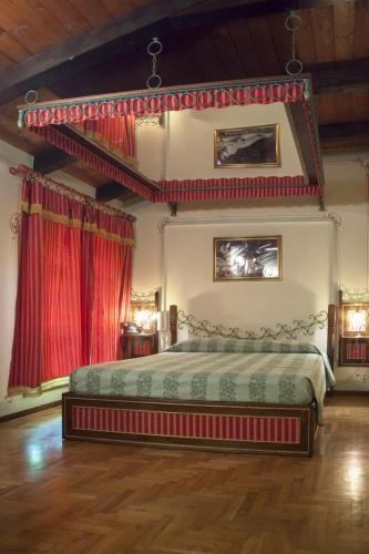 a bedroom with a king sized bed with red curtains at Hotel Villino Della Flanella in Modena