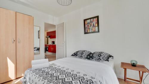 Schlafzimmer mit einem Bett mit einer schwarzen und weißen Bettdecke in der Unterkunft Chic apart with parking and balcony near Paris in Aubervilliers
