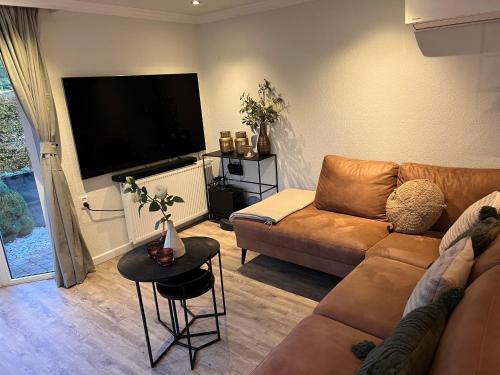 a living room with a couch and a flat screen tv at Ibiza Style Holiday chalet in Susteren