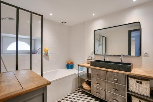 une salle de bain avec un lavabo, une baignoire et un miroir dans l'établissement Vue exceptionnelle - Accès privé front de mer, à La Ville-ès-Nonais