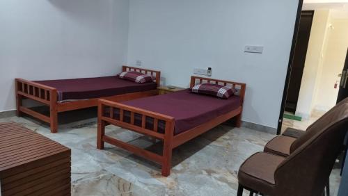 twee bedden in een kamer met een stoel bij Aptha Ayurveda in Kadikkād
