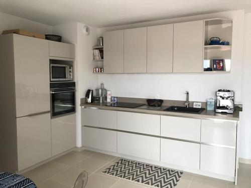 une cuisine avec des armoires blanches et un comptoir dans l'établissement Charmant appartement de type 3 au deuxieme étage, à Gujan-Mestras