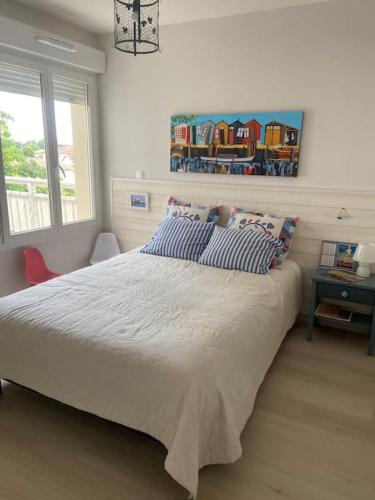 ein Schlafzimmer mit einem großen Bett mit blauen und weißen Kissen in der Unterkunft Charmant appartement de type 3 in Gujan-Mestras