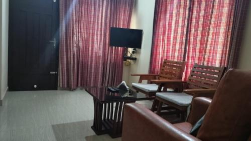 a waiting room with chairs and a table and a tv at Aptha Ayurveda in Kadikkād