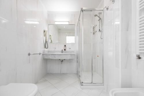 a white bathroom with a shower and a sink at Hotel Sogno del Benaco in Limone sul Garda