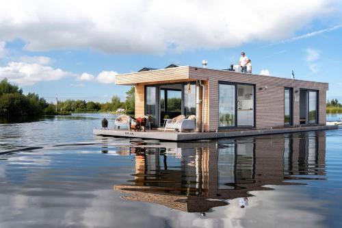 a tiny house on a floating dock in the water at Surla Houseboat De Saek with tender in Monnickendam