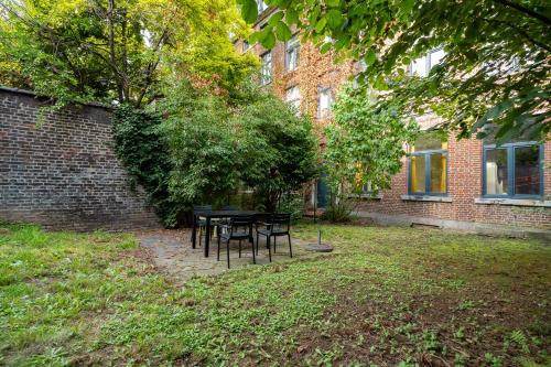 une table et des chaises devant un bâtiment en briques dans l'établissement Maison 4 chambres avec jardin, à Liège