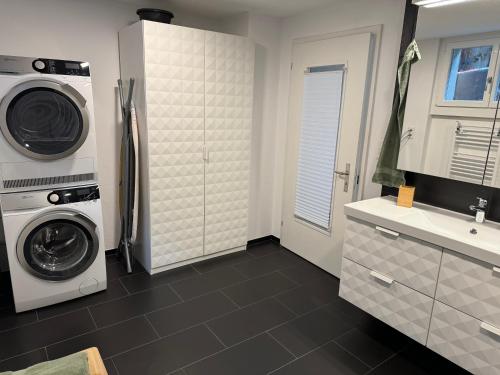 a kitchen with a refrigerator and a washer and dryer at See und Berge Garden in Faulensee