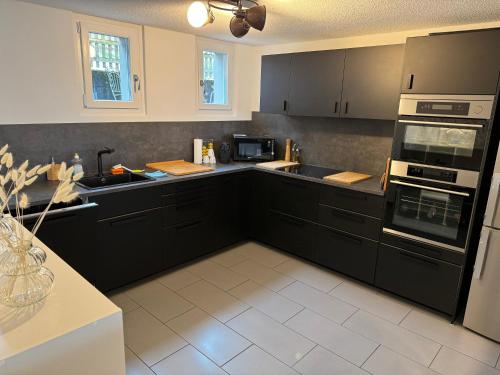 a kitchen with black cabinets and black appliances at See und Berge Garden in Faulensee