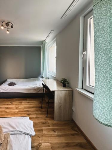 a bedroom with a bed and a desk and a window at Kwadrat B&B Spiechowicza in Rzeszów