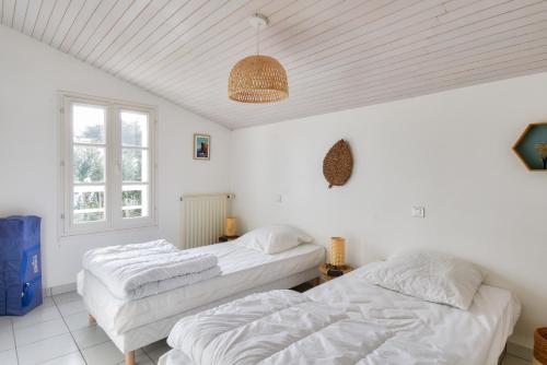 two beds in a room with white walls at Maison pour 14 - 150 m de la plage de la Clère in Noirmoutier-en-l'lle