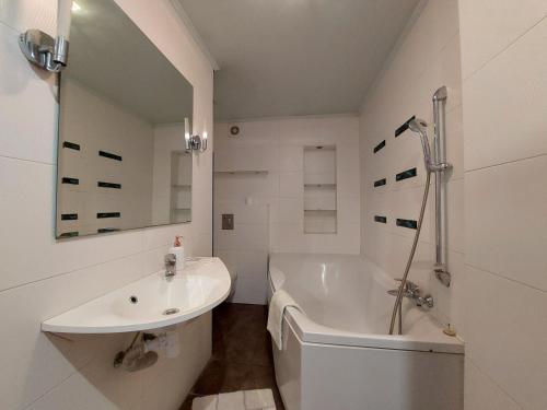 La salle de bains blanche est pourvue d'une baignoire, d'un lavabo et d'une baignoire. dans l'établissement Двокімнатні апартаменти у центрі, à Loutsk