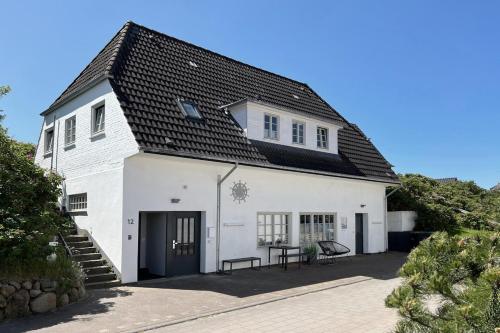 a white building with a black roof at Sylter Glanz Kommissar Feldmann in Hörnum