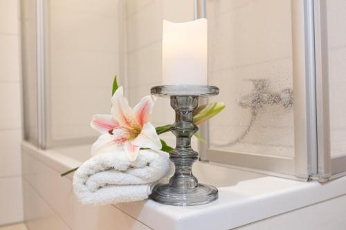 una candela e un fiore sullo scaffale del bagno di Haus Ohragrund a Oberhof