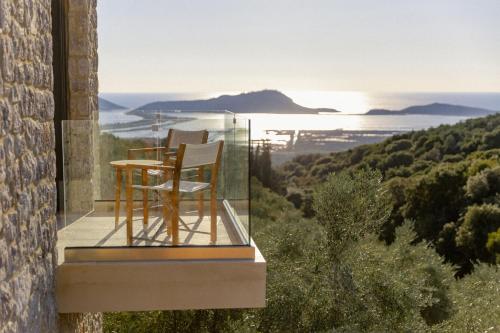 a glass house with a table and a chair on a balcony at Messinian Nest in Gialova
