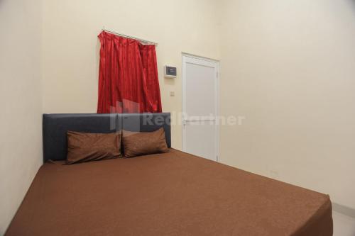 a bedroom with a bed with a red curtain at Rawa Buntu House RedPartner in Ciater-hilir