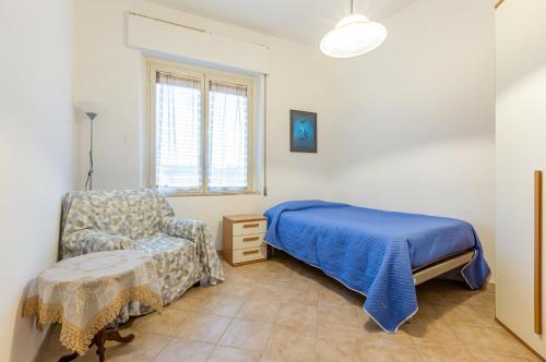 Monserrato Cozy Apartment near the Policlinico! في مونسيرّاتو: غرفة نوم بسرير وكرسي