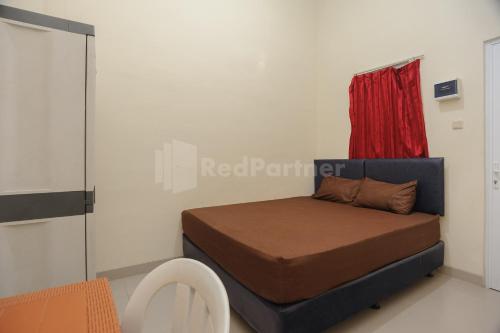 a bedroom with a bed with a red curtain at Rawa Buntu House RedPartner in Ciater-hilir