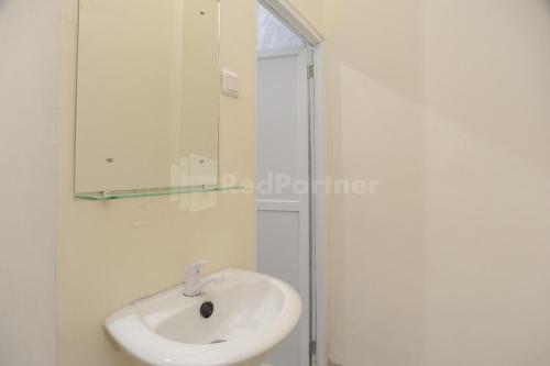 a white bathroom with a sink and a mirror at Rawa Buntu House RedPartner in Ciater-hilir
