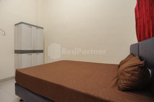 a bedroom with a bed and a red curtain at Rawa Buntu House RedPartner in Ciater-hilir