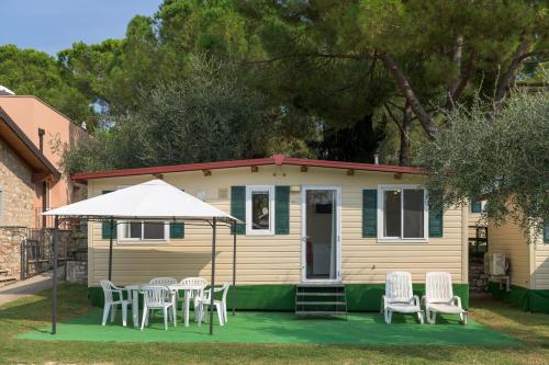a small yellow house with chairs and an umbrella at Camping Toscolano in Toscolano Maderno