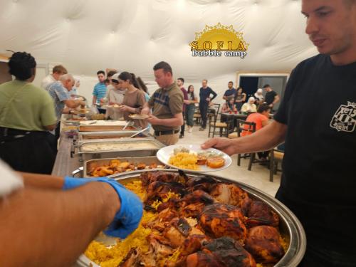um homem segurando um prato de comida em um buffet em Bubble Sofia Luxury Rum Camp em Wadi Rum