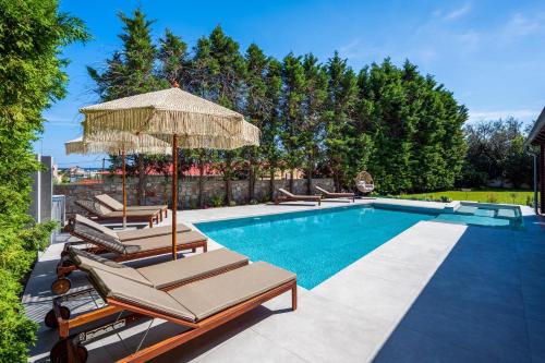 a swimming pool with lounge chairs and an umbrella at 3 Roses Residence in Afantou