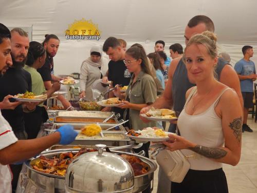 a group of people holding plates of food at Bubble Sofia Luxury Rum Camp in Wadi Rum