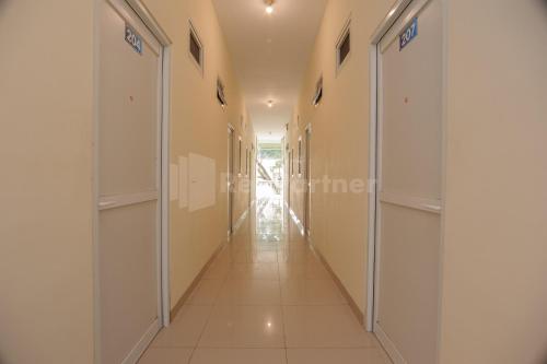 a corridor of a building with white walls and a long hallway at Rawa Buntu House RedPartner in Ciater-hilir