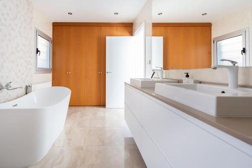 baño blanco grande con 2 lavabos y bañera en Villa Paraíso, en Castelldefels