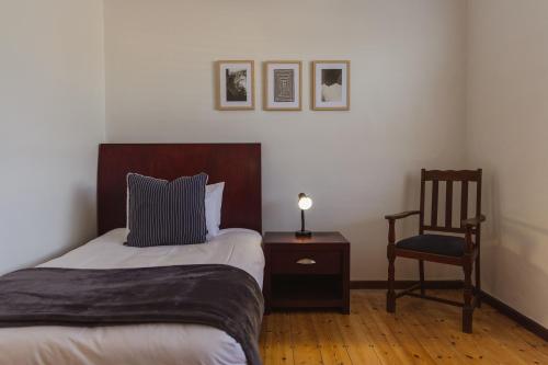 a bedroom with a bed and a chair and a lamp at Beachside Cottage in Bloubergstrand