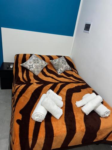 uma cama com um cobertor de listras de tigre e duas toalhas em Marrakech rooms 2 em Catânia